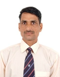 Portrait of Dr. Kapoor wearing traditional attire with academic books in background